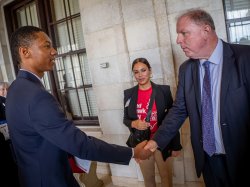 Two men shake hands as a woman in a Red Hawk Day t-shirt looks on.