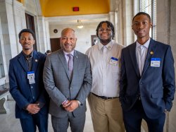 Three young men and a legislator pose for a picture.