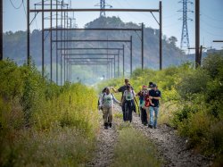 10 people walk on a trail that was once a rail road.