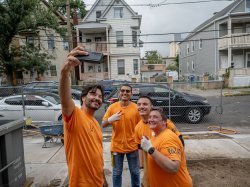 Montclair 总统 Jonathan Koppell taking a selfie with three volunteers at a Habitat for Humanity construction site during the 9/11 Day of Service.