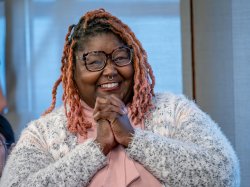 Khara Brown clasps her hands together in an expression of joy and gratitude.