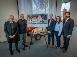 Five people standing with sign in the center promoting One Square Mile initiative