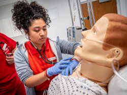 Female nursing student in simulation lab with medical manikin.