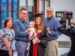 Female RN to BSN student at commencement with family.