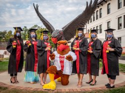 Faculty, students, and Rocky posing for celebratory photograph following commencement.