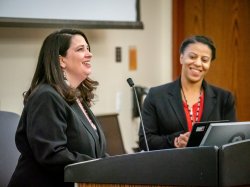 Dr. Nastassia Davis and Jill Wodnick standing behind a podium with a microphone.