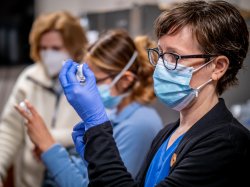 Close up image of masked and gloved nursing student filling a syringe.