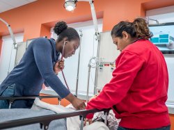 Two female nursing students in the Simulation Center standing over a medical manikin.