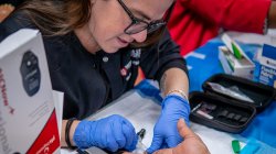 School of Nursing alumni taking a fingerstick sample during a health screening.