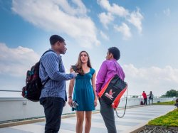Three students standing and talking outside of a building on campus.