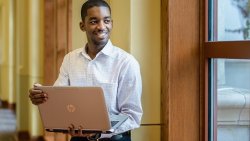 Student standing while holding laptop computer