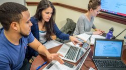 3 students at table working on a collaborative presentation