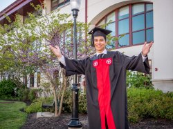 Montclair student with cap and gown on campus