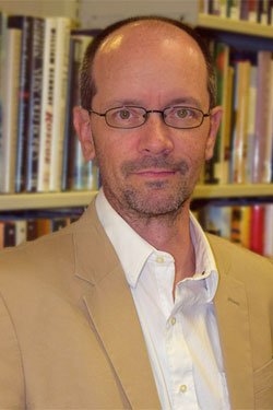 photo of professor Ian Drake with full bookcase in background