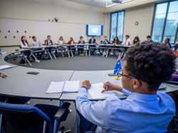students seated at a round table with flags of different countries