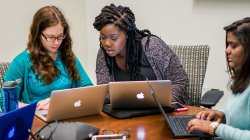 Photo of three students with macbooks