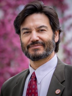 Montclair State University President Jonathan Koppell poses by a blooming tree on campus.