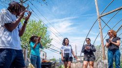 tour guide speaks to a group of people at a community garden