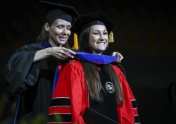 photo of PhD student Brooke Stettler being hooded at Commencement ceremony