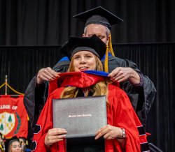 photo of doctoral student Alaina Wodzinski being hooded at Commencement