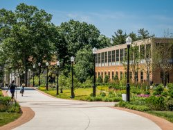 Students walking by Sprague Library and Life Hall on a summer day.