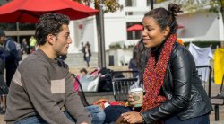 Image of two students sitting and talking outside the student center.