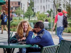 Two students sitting outside of Cafe Diem looking at something on a laptop.