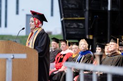 student in cap and gown at podium