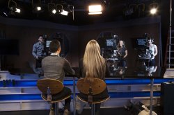 newscasters at desk from behind