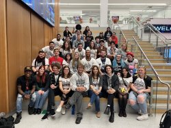 A group of students sitting on stairs in six rows in an academic building.