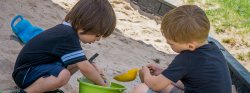 Image of two children playing in a sandbox.