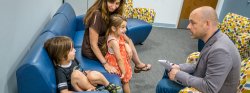 Image of a clinician talking with a parent and two children in a clinical setting.
