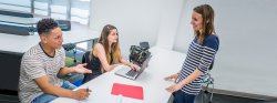 Image of two students and a faculty member in a classroom setting.