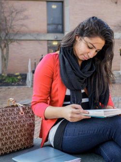Photo of a student studying outside on campus in the fall.