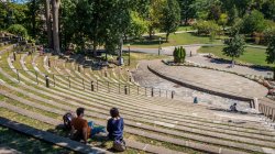Wideshot of two students sitting in the campus amphitheater outside.
