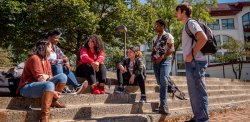 students sitting on steps in front of college hall.