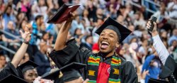 student in cap and gown waving during commencement