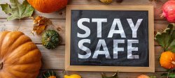 Picture of a Thanksgiving holiday table with pumpkins and a sign that reads Stay Safe.