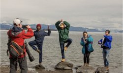 Man taking picture of students on rocks posing