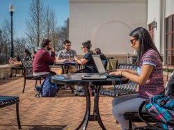 Photo of student working on her laptop at outside table.