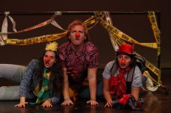 A group of young performers on stage with clown noses and hats