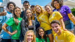 Group of students smiling and laughing in different colored t-shirts on Red Hawk Day