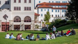 A teacher standing and students sitting on grass at Montclair State University Feliciano School of Business at Spring