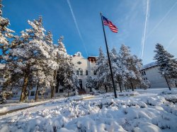 College Hall in snow with trees and flagpole.