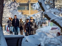 Students bundled up and walking along campus path blanketed by snow.