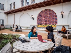 two women talking at an outdoor table on campus
