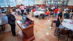 teacher stands in front of conference room full of students