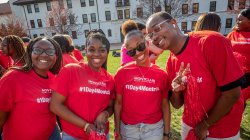 Four students smiling, wearing red tees that read #1Day4Montclair