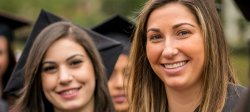 two smiling graduates in cap and gowns