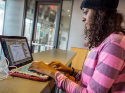 Photo of a student writing on a laptop computer.